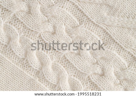 Background Of White Knitted Fabric Of Wool With Patterns Close Up.