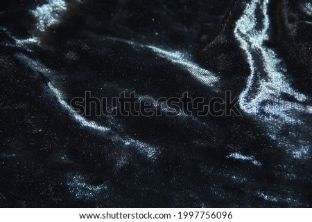 Blue-black shiny velvet. Pleats on the fabric. Backgrounds
