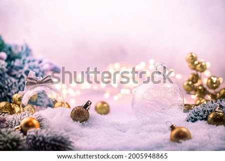 Christmas gold decorations on snow with fir tree branches and christmas lights. Winter Decoration Background