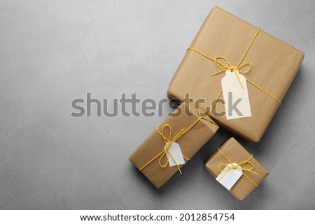 Parcels wrapped in kraft paper with tags on light grey table, flat lay. Space for text