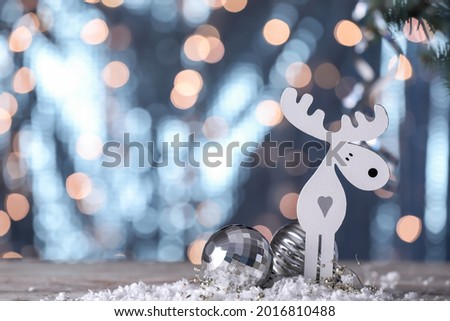 Christmas decor and snow on table against blurred lights