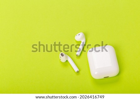 white wireless earphones with charging case on green background