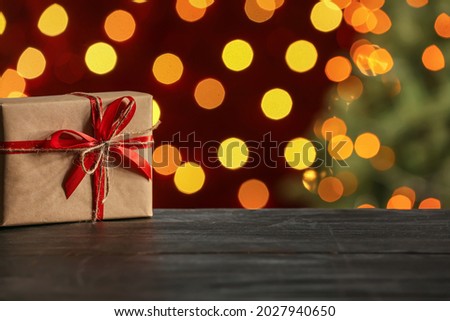 Gift box on table against blurred Christmas lights