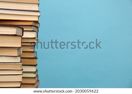 Many hardcover books on turquoise background, space for text. Library material