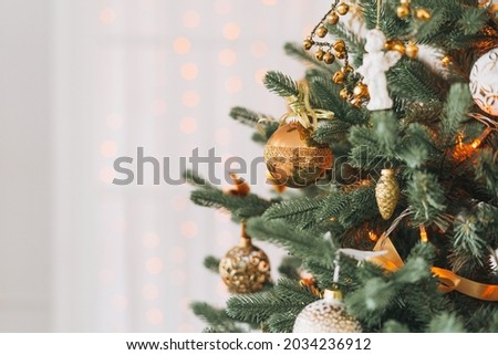 Decorated Christmas tree in golden and white toys with lights bokeh textured background