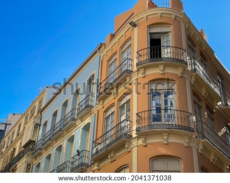 Beautiful orange and blue bright facades of historical architecture buildings with tiny balconies and windows in old town of Malaga, Spain