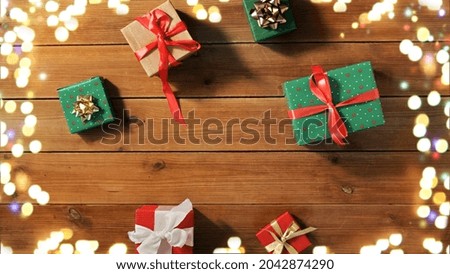christmas, holidays and celebration concept - gift boxes on wooden boards from top over festive lights