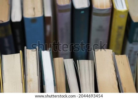 A stack of used books of different thicknesses on the shelf in the library, selective focus