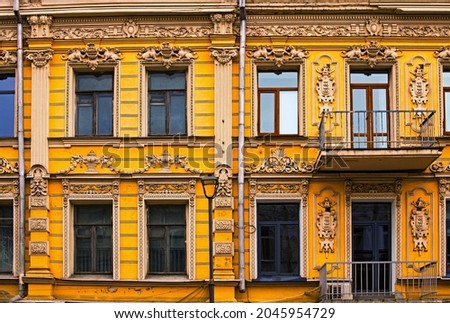 One of the most beautiful facades in Peter Sagaidachny Street in Kyiv. Six windows and two doors to the balconies. Old yellow building in street. The wall decorated by fretwork. Kyiv, Ukraine.
