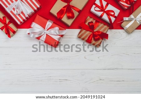 Festive layout with a copy space. Above view of decorated gift boxes and red wrapping paper on white wooden background.