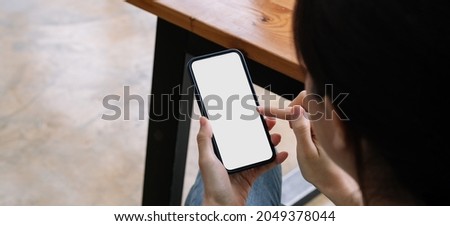 Woman sitting and holding blank screen mock up mobile phone.
