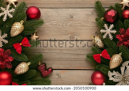 Christmas frame - tree branches with red and gold baubles, stars, snowflakes on grey background. Top view