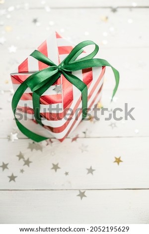 Christmas gift box, striped red and white wrapping paper with green bow, on a white background
