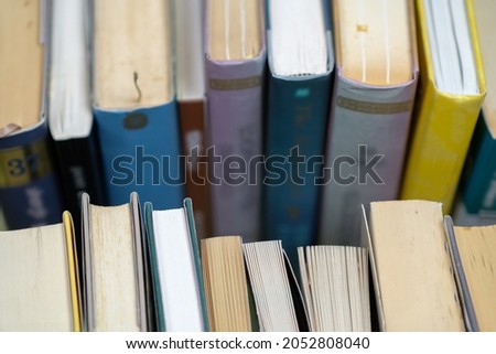A stack of used books of different thicknesses on the shelf in the library, selective focus
