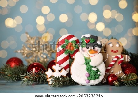 Sweet Christmas cookies and decor on light blue table against blurred festive lights