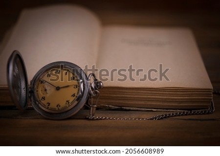 Open vintage book with blank sheets and a watch on wood table