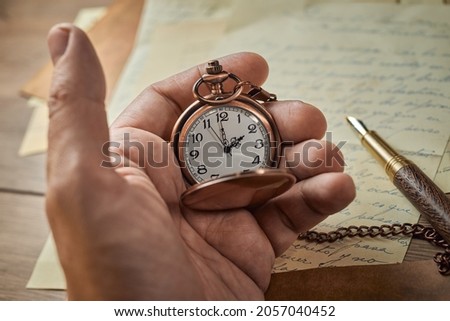 Old watch in the male hand, papers, letters, envelopes