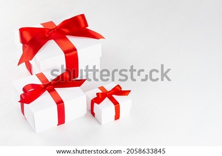 Elegant white present boxes different size with red ribbon on wood table, top view, copy space.