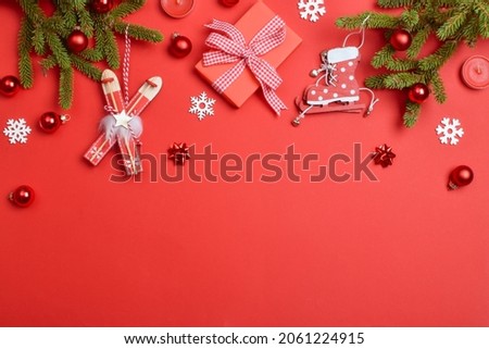Christmas background with gifts, glass balls and fir branches on a red background. New Year's composition of Christmas decorations. Flat lay, top view.