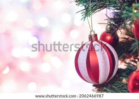 Christmas decoration. Red balls hanging on pine branches Christmas tree garland and ornaments over abstract bokeh background with copy space

