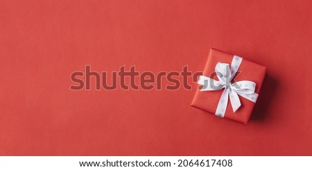 Gift boxe with white bow on a red backdrop. Top view.