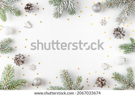 Christmas or Happy New Year composition. Frame made of fir tree branches, holiday silver and golden decorations on white background. Flat lay. Top view with copy space