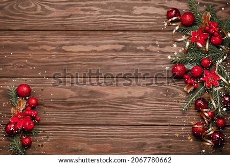 Festive Christmas background red balls green branches spruce serpentine sequins wooden dark background.