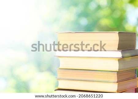 Stack of books on blurred background, space for text. Bokeh effect 