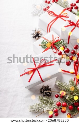 Christmas gift boxes with decorations on white tablecloth.