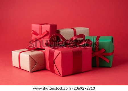 Heap of Christmas presents in colorful packaging on a red background, close-up.