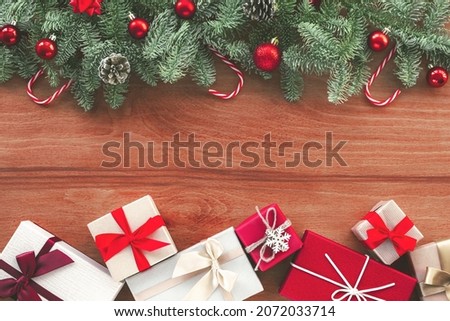 Christmas background with fir branches, new year decorations and gift boxes on wooden backdrop. Top view, flat lay, copy space.