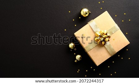 Merry Christmas and Happy New Year banner design. Gift box, golden baubles decorations, confetti on dark black background.