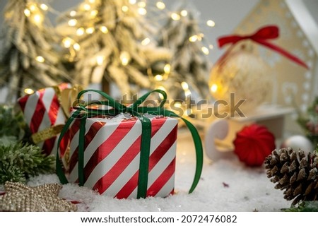 Christmas striped gift box with green ribbon bow, light bokeh, winter decorations