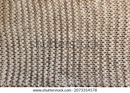 Knitted background in beige color. Knitted beige blanket. Warm knitted background.