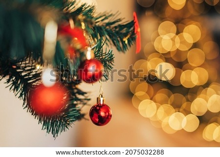 Artificial Christmas tree branch with red baubles and garland in front of the mirror.