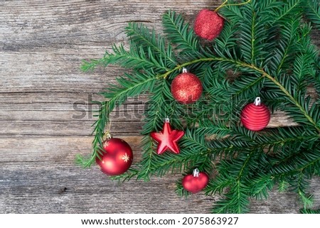 Rustic christmas lifestyle - evergreen twig decorated with red balls on aged wooden background