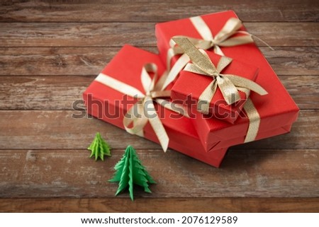 winter holidays, new year and celebration concept - red gift boxes and origami christmas trees on wooden boards background