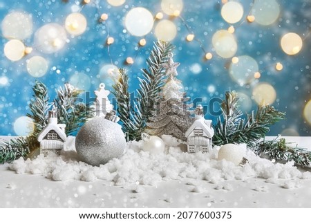 Abstract Advent Christmas Background. Winter decorations ornaments toys and balls on blue background with snow and defocused garland lights. Merry Christmas time concept.