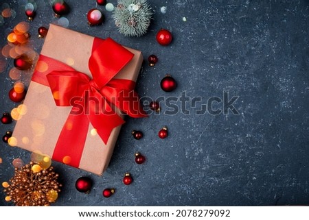 christmas gift box with red ribbon and red christmas balls on the black stone background