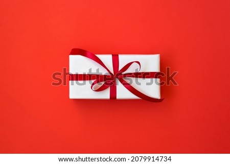 Christmas background with gift box over red backdrop. Christmas celebration, preparation for winter holidays, secret Santa, advent calendar concept. Top view, flat lay