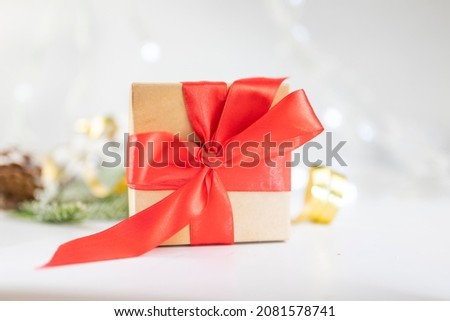beautiful festive surprise gift box with a red bow on a bokeh background and near the Christmas tree for new year and valentine's day