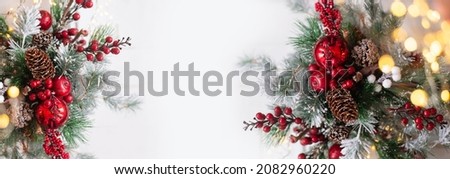 Beautiful Christmas background. Spruce branches with red decorations on a white background.