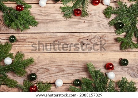 Christmas frame made of fir branches and balls on wooden background. Copy space, top view.