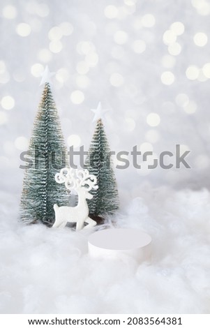Podium or pedestal mok-up for cosmetics in the snow with a christmas tree on a bokeh background vertical format