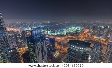 Aerial skyline with Golf Club, junction, hotels and residential areas far away in desert in Dubai night timelapse, UAE, top view from Dubai marina skyscrapers