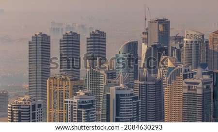 JLT skyscrapers near Sheikh Zayed Road aerial timelapse. Residential buildings and villas with morning haze