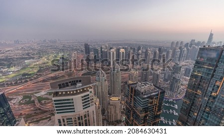 Panorama of Dubai Marina with JLT skyscrapers and golf course day to night transition timelapse, Dubai, United Arab Emirates. Aerial view from above towers after sunset