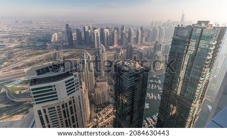 Panorama of Dubai Marina with JLT skyscrapers and golf course timelapse, Dubai, United Arab Emirates. Aerial view from above towers. City skyline with hazy weather