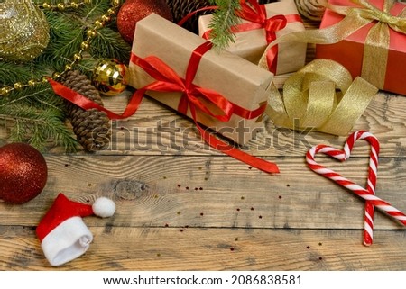 Beautiful Christmas wooden background with Christmas decorations, boxes with gifts and caramel canes. Natural spruce branches and cones.