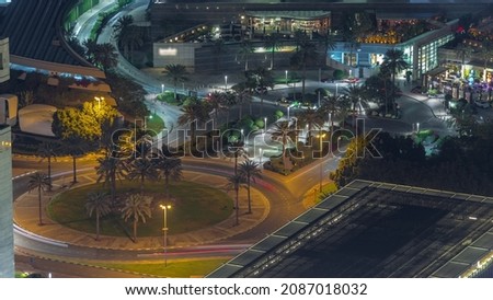 Aerial view of a roundabout circle road in Dubai financial district from above night timelapse. Traffic on the street with palms. Dubai, United Arab Emirates.